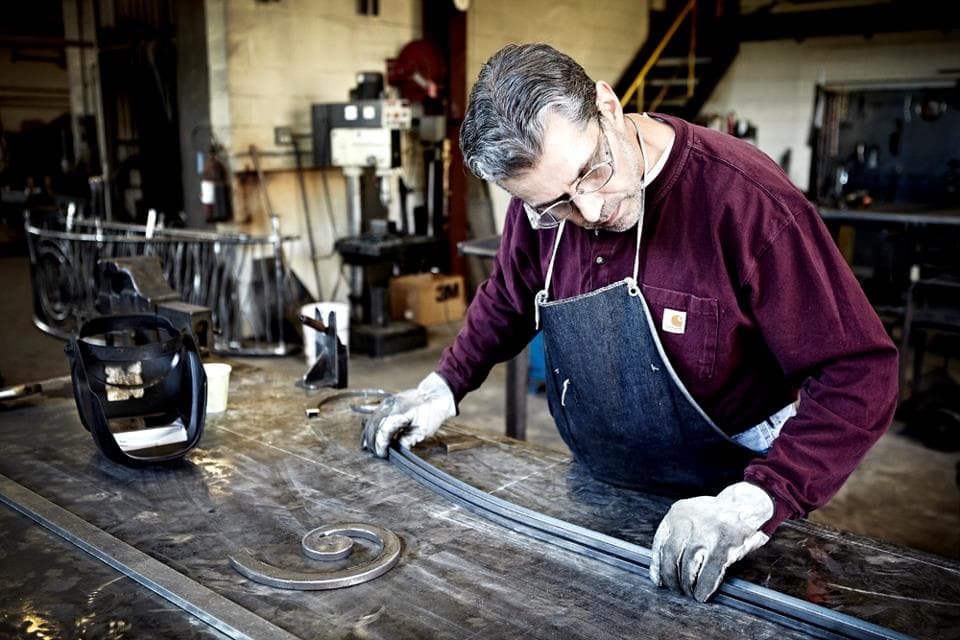 Craftsman shaping iron at the workbench